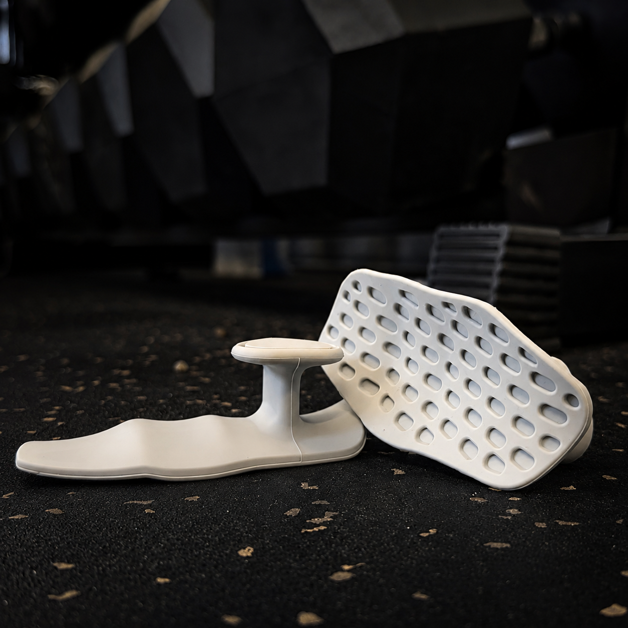 White LiftGrips workout grips shown from the front and side on a dark gym floor