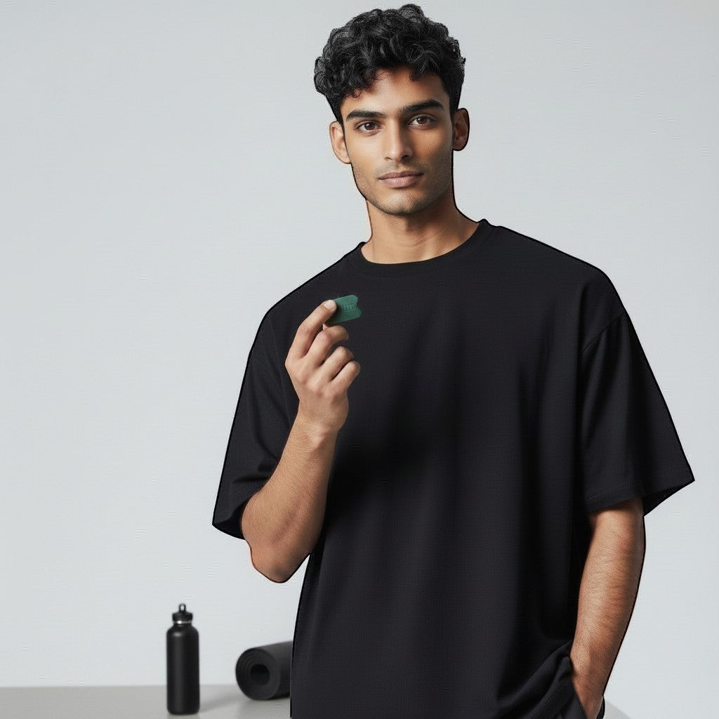 Dropset™ Official man holding green JawFlex jaw exerciser, wearing black t-shirt. Fitness equipment in background.