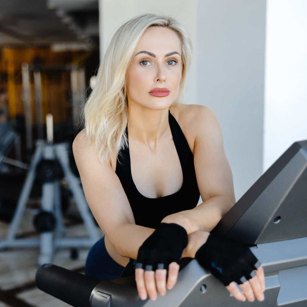 Woman sitting on a treadmill in a gym setting