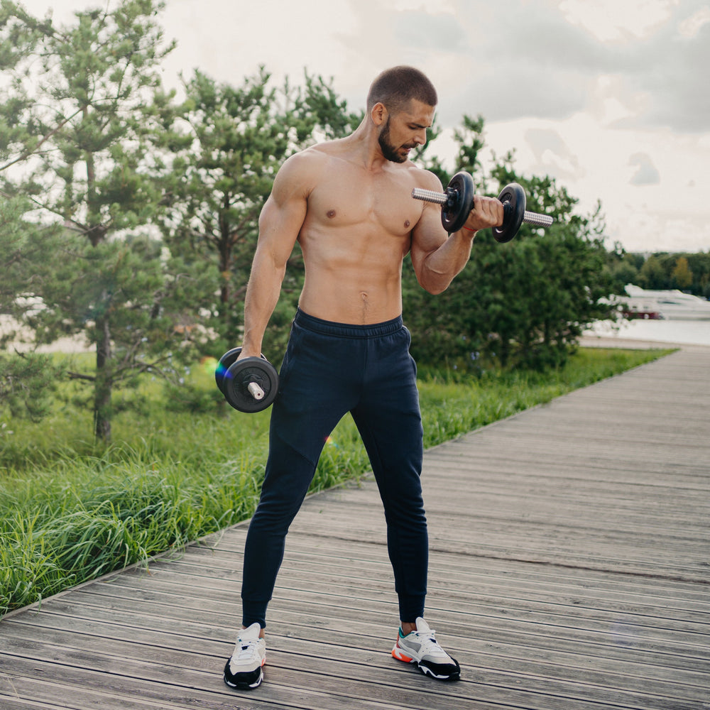 Man exercising with dumbbells on a wooden path outdoors